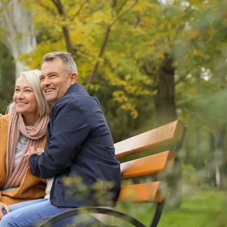 An older couple on a park bench in autumn
