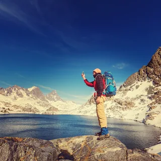A hiker with a backpack above a mountain lake